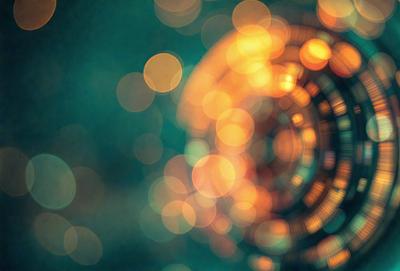 The primary subject of the image is a brightly lit, colorful circle. The circle is surrounded by a green background, giving the scene a vibrant and lively atmosphere. The visual style of the image is a combination of photo and digital art, creating a unique and eye-catching effect. The colors and mood of the image are predominantly warm and inviting, with the bright lights and green background creating a sense of energy and liveliness.