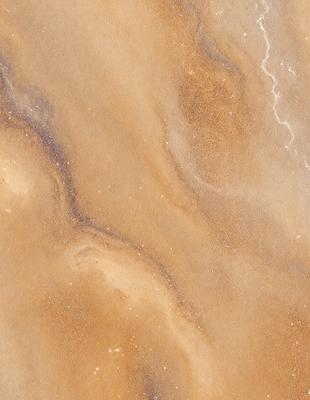 The primary subject of the image is a close-up of a brown and tan marble surface. The setting is a natural environment, with the marble surface being the main focus. The visual style is a close-up, which emphasizes the intricate details of the marble. The colors and mood of the image are warm and earthy, with the brown and tan tones creating a natural and organic atmosphere.