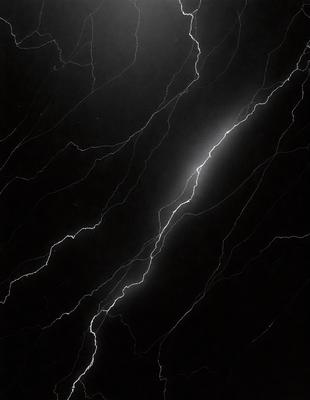 The primary subject of the image is a lightning bolt, which is the main object, scene, or focus of the image. The lightning bolt is captured in a black and white photo, giving it a dramatic and artistic visual style. The setting or background of the image is a black marble surface, which adds to the overall atmosphere and mood of the photo.
