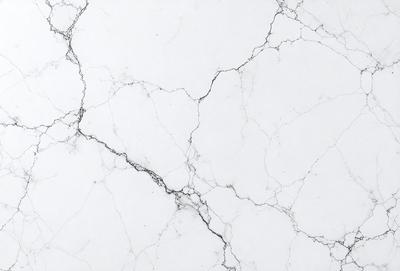 The primary subject of the image is a white marble wall with a pattern of cracks and crevices. The setting is a room with a white marble floor. The visual style is a close-up of the marble wall, showcasing its unique texture and pattern. The colors and mood of the image are predominantly white, giving it a clean and elegant appearance.
