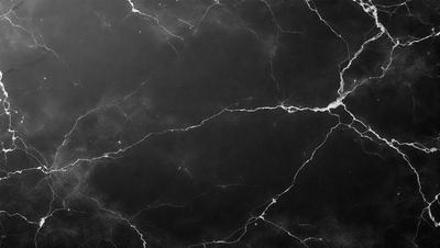 The primary subject of the image is a black marble countertop. The setting is a kitchen, with the countertop being the main focus of the scene. The visual style is a close-up of the marble countertop, showcasing its texture and details. The colors and mood of the image are dark and moody, with the black marble countertop being the dominant color.
