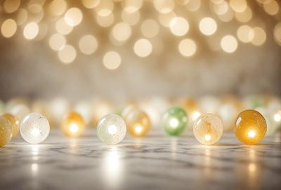The primary subject of the image is a group of lighted balls, which are placed on a table. The setting is a white background, and the visual style appears to be a photo. The balls are illuminated, and the dominant colors are yellow and green. The overall atmosphere of the image is bright and cheerful.