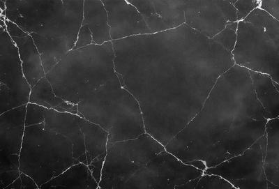 The primary subject of the image is a black marble countertop. The setting is a dark room, and the visual style is a close-up of the marble countertop. The countertop has a black and white pattern, and the overall atmosphere is dark and moody.