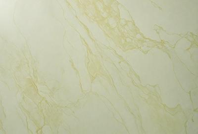 The primary subject of the image is a marble wall with a yellowish tint. The setting is a room with a white background. The visual style is a close-up of the marble wall, showcasing its texture and color. The dominant colors are yellow and white, creating a warm and elegant atmosphere.