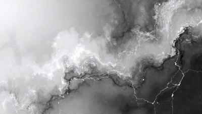 The primary subject of the image is a cloudy sky with lightning bolts streaking through it. The setting is a dark, cloudy background, and the visual style is a black and white photo. The dominant colors are shades of gray and black, creating a moody atmosphere.