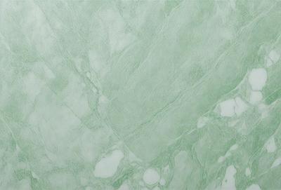 The image features a green marble wall with a pattern of white and green swirls. The wall appears to be a part of a bathroom, as it is a large, smooth surface. The overall atmosphere of the image is serene and elegant, with the combination of the green marble and the white and green swirls creating a visually appealing and luxurious environment.
