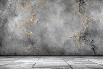 The primary subject of the image is a large gray wall with a pattern of yellow streaks. The setting is a room with a concrete floor, and the visual style is a photo. The dominant colors are gray and yellow, creating a moody atmosphere.
