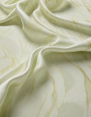 The primary subject of the image is a white sheet of fabric with a pattern of gold and brown swirls. The setting is a room with a table, and the visual style is a close-up of the fabric. The colors and mood of the image are warm and inviting, with the gold and brown swirls adding a touch of elegance and sophistication to the overall atmosphere.