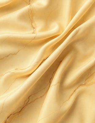 The primary subject of the image is a yellow fabric, possibly a piece of silk, with a marbled texture. The setting is a close-up of the fabric, showcasing its unique pattern and texture. The visual style is a detailed, up-close view of the fabric, highlighting its intricate design. The colors and mood of the image are warm and inviting, with the yellow fabric serving as the main focus.