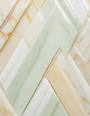 The primary subject of the image is a marble tile with a gold trim. The setting is a wall, and the visual style is a close-up of the tile. The colors and mood of the image are predominantly white and gold, giving it a luxurious and elegant appearance.