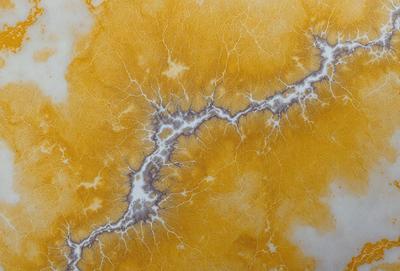 The primary subject of the image is a yellow and orange marbled surface, which appears to be a piece of marble or a similar material. The setting is a close-up view of the marbled surface, showcasing its unique texture and pattern. The visual style of the image is a close-up, which emphasizes the intricate details of the marbled surface. The colors and mood of the image are warm and inviting, with the yellow and orange hues creating a sense of warmth and natural beauty.