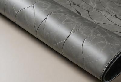 The primary subject of the image is a piece of fabric, which appears to be a gray or silver material. The setting is a table, and the visual style is a close-up of the fabric. The colors and mood of the image are predominantly gray and neutral, giving it a calm and sophisticated appearance.