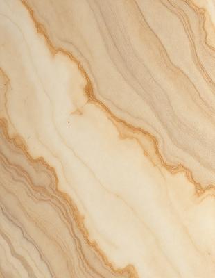 The primary subject of the image is a marble surface with a pattern of swirls and curves. The setting is a room with a wooden floor, and the visual style is a close-up of the marble surface. The colors and mood of the image are warm and natural, with the marble surface being the main focus.