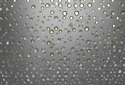 The primary subject of the image is a close-up of a surface covered in small, round, clear bubbles. The setting appears to be a white, possibly textured, background. The visual style of the image is a close-up of the bubbles, creating a sense of depth and detail. The colors and mood of the image are predominantly white, giving it a clean and fresh appearance.