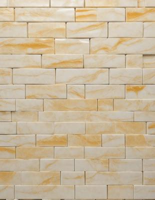 The primary subject of the image is a large, white marble wall with a pattern of yellow and white tiles. The setting is a room with a white brick wall, which adds to the overall visual style. The colors and mood of the image are predominantly white and yellow, creating a clean and bright atmosphere.
