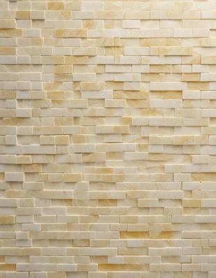 The primary subject of the image is a large, white brick wall. The setting is a room with a yellow brick wall, which adds a warm and earthy tone to the space. The visual style is a close-up of the brick wall, showcasing its texture and pattern. The colors and mood of the image are predominantly yellow and warm, creating a cozy and inviting atmosphere.