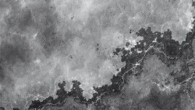 The primary subject of the image is a black and white photo of a cloudy sky. The setting is a gray, cloudy background, which adds to the overall atmosphere of the photo. The visual style is a black and white image, giving it a classic and timeless appearance. The colors and mood of the photo are predominantly dark and moody, with the clouds and sky creating a dramatic and atmospheric scene.