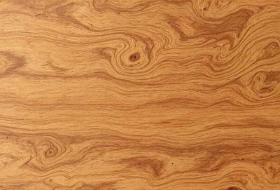 The primary subject of the image is a wooden surface with a unique and intricate pattern. The setting is a wooden table, and the visual style appears to be a close-up of the wooden surface. The colors and mood of the image are warm and natural, with the wooden surface being the main focus.