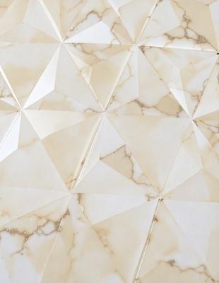 The primary subject of the image is a marble wall with a geometric pattern. The setting is a room with a white marble wall, and the visual style is a close-up of the wall. The colors and mood of the image are predominantly white, giving it a clean and elegant appearance.