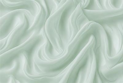 The primary subject of the image is a white, flowing fabric that appears to be a sheet of silk. The setting is a green background, which adds a sense of depth and contrast to the scene. The visual style is a close-up of the fabric, showcasing its texture and details. The colors and mood of the image are predominantly white and green, creating a serene and elegant atmosphere.
