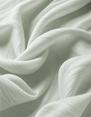 The primary subject of the image is a white, flowing fabric that appears to be a sheet of silk. The setting is a white background, which creates a clean and minimalist appearance. The visual style is a close-up of the fabric, showcasing its texture and details. The colors and mood of the image are predominantly white, giving it a serene and elegant feel.