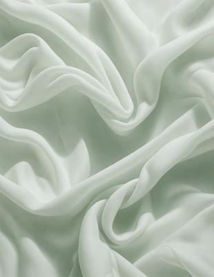 The primary subject of the image is a white sheet of fabric, which is the main object, scene, or focus of the image. The setting or background is a white surface, which provides a clean and minimalistic backdrop for the fabric. The visual style of the image is a close-up of the fabric, showcasing its texture and details. The colors and mood of the image are predominantly white, giving it a clean, serene, and calming atmosphere.