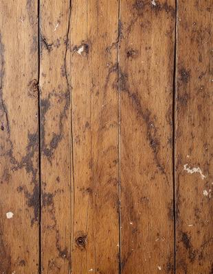 The primary subject of the image is a wooden floor with a worn and aged appearance. The setting is indoors, possibly in a room with a wooden floor. The visual style is a close-up of the wooden floor, showcasing its texture and details. The colors and mood of the image are predominantly brown and earthy, giving it a rustic and aged feel.