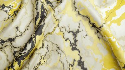 The primary subject of the image is a marble-patterned fabric. The setting is a close-up of the fabric, showcasing its intricate design. The visual style is a detailed, textured image that highlights the marble pattern. The colors and mood of the image are predominantly yellow and white, giving it a warm and elegant appearance.