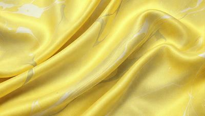 The primary subject of the image is a yellow fabric, possibly a silk scarf, with a pattern of swirls and waves. The setting is a close-up of the fabric, showcasing its intricate design. The visual style is a detailed, artistic representation of the fabric, possibly a digital art or illustration. The colors and mood of the image are predominantly yellow, creating a warm and vibrant atmosphere.