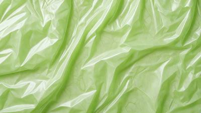 The primary subject of the image is a green plastic sheet, which is the main object, scene, or focus of the image. The setting/background consists of a green surface, possibly a table or a wall, where the plastic sheet is placed. The visual style of the image is a close-up of the green plastic sheet, showcasing its texture and color. The colors and mood of the image are predominantly green, giving it a fresh and natural appearance.