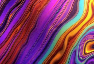 The primary subject of the image is a colorful, swirling pattern that resembles a painting or a digital artwork. The setting is a purple and blue background, which adds to the vibrant and lively atmosphere of the scene. The visual style appears to be a combination of photo and digital art, creating a unique and eye-catching image. The dominant colors are purple, blue, and orange, which contribute to the overall mood of the image, evoking a sense of energy and creativity.