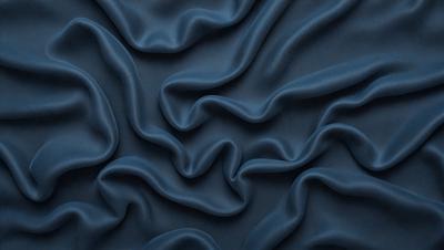 The primary subject of the image is a blue fabric with a wavy pattern. The setting is a dark background, which contrasts with the blue fabric. The visual style is a close-up of the fabric, showcasing its texture and pattern. The colors and mood of the image are predominantly dark and moody, with the blue fabric serving as the focal point.