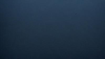 The primary subject of the image is a dark blue sky with no clouds. The setting is a vast, open space with no visible landmarks or objects. The visual style is a simple, unadorned representation of the sky. The colors and mood are predominantly dark and moody, with the blue sky serving as the main focal point.