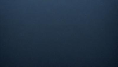 The primary subject of the image is a dark blue sky with no clouds. The setting is a vast, open space with no visible landmarks or objects. The visual style is a simple, unadorned representation of the sky. The colors and mood are predominantly dark and moody, with the blue sky being the main focus of the image.