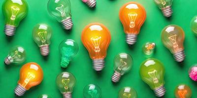 The primary subject of the image is a collection of light bulbs, which are displayed in various colors and sizes. The setting is a green background, which provides a contrasting and vibrant backdrop for the light bulbs. The visual style of the image is a combination of photo and digital art, as it showcases the light bulbs in a visually appealing manner. The colors and mood of the image are lively and energetic, as the light bulbs create a sense of brightness and positivity.