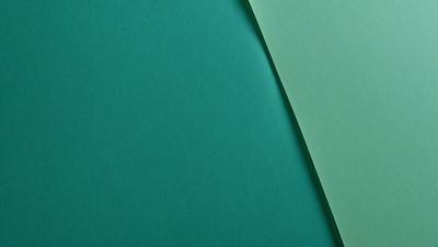 The primary subject of the image is a green piece of paper. The setting is a table, and the visual style is a photo. The colors and mood of the image are predominantly green, creating a calm and soothing atmosphere.