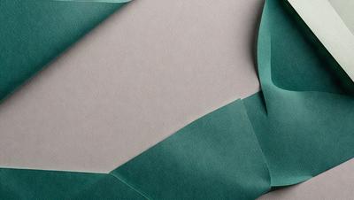 The primary subject of the image is a green paper, which is the main object, scene, or focus of the image. The setting/background consists of a tan surface, which provides a contrasting backdrop for the green paper. The visual style of the image is a close-up of the green paper, showcasing its texture and details. The colors and mood of the image are predominantly green, with a slightly earthy tone, creating a calm and natural atmosphere.