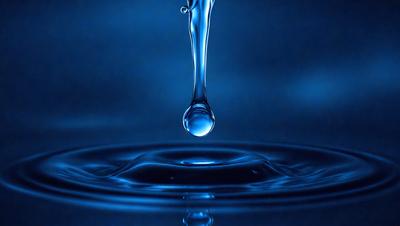 The primary subject of the image is a single drop of water, which is captured in mid-air. The setting is a dark blue background, which creates a striking contrast with the water drop. The visual style is a close-up of the water drop, emphasizing its details. The colors and mood of the image are predominantly dark and moody, with the blue background and the water drop creating a sense of depth and intensity.