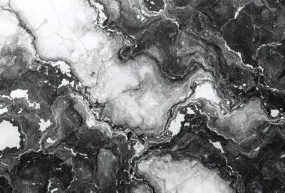 The image is a black and white photo of a marble surface with a pattern of swirls and curves. The primary subject is the marble, which is the main object, scene, or focus of the image. The setting/background is a marble surface, and the visual style is a photo. The colors and mood are predominantly black and white, giving the image a classic and timeless appearance.