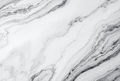 The image features a marble countertop with a white and gray color scheme. The countertop has a patterned design, giving it a unique and elegant appearance. The setting is a kitchen or bathroom, as the countertop is a common surface in these spaces. The visual style of the image is a close-up, allowing the viewer to appreciate the intricate details of the marble countertop. The colors and mood of the image are calming and sophisticated, creating a sense of luxury and refinement
