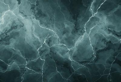 The primary subject of the image is a close-up of a blue and black marbled wall. The setting is a dark room with a blue and black marbled wall as the main focus. The visual style is a close-up of the wall, which gives a sense of depth and texture. The colors and mood of the image are predominantly dark and moody, with the blue and black marbled wall creating a striking contrast against the dark background.