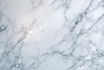 The primary subject of the image is a marble wall with a white and grey color scheme. The setting is a room with a white marble surface, which adds a sense of elegance and sophistication to the space. The visual style of the image is a close-up of the marble wall, showcasing its intricate patterns and textures. The colors and mood of the image are predominantly white and grey, creating a clean and minimalist atmosphere.