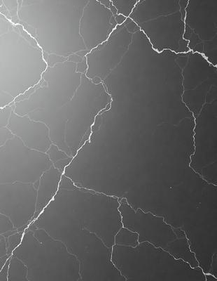 The primary subject of the image is a close-up of a black marble surface with a pattern of white streaks. The setting is a dark room, and the visual style appears to be a photo. The dominant colors are black and white, creating a moody atmosphere.