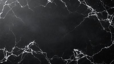 The primary subject of the image is a black marble countertop. The setting is a dark room, and the visual style is a close-up of the marble countertop. The countertop has a patterned texture, and the colors are predominantly black. The overall atmosphere is elegant and sophisticated.