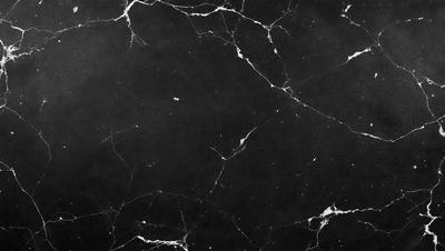 The primary subject of the image is a black marble countertop. The setting is a dark room, and the visual style is a close-up of the marble countertop. The countertop has a pattern of white spots, giving it a unique and elegant appearance. The overall atmosphere is sophisticated and luxurious.