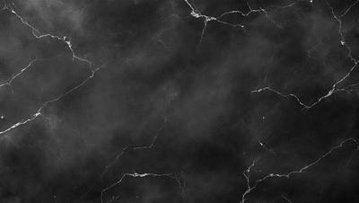 The image is a black and white photo of a marble surface, possibly a countertop or a wall. The marble surface has a pattern of holes, giving it a unique and textured appearance. The overall atmosphere of the image is dark and moody, with the black and white color scheme adding to the dramatic effect.