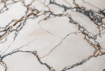 The primary subject of the image is a marble countertop with a gold-like pattern. The setting is a kitchen, and the visual style is a close-up of the marble countertop. The colors and mood of the image are predominantly white and gold, giving it a luxurious and elegant appearance.