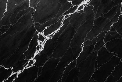 The primary subject of the image is a close-up of a marble surface with a black background. The marble surface features a pattern of white and black veins, giving it a unique and natural appearance. The visual style of the image is a close-up, which emphasizes the intricate details of the marble pattern. The colors and mood of the image are predominantly black and white, creating a sense of elegance and sophistication.