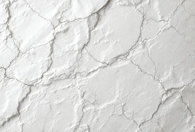 The image features a white wall with a textured surface, giving it a slightly rough appearance. The wall is adorned with a pattern of holes, which adds to the visual interest of the scene. The primary subject of the image is the white wall, which serves as the main focus of the image. The setting is indoors, and the visual style is a close-up of the wall, showcasing its unique texture and pattern. The colors and mood of the image are predominantly white, giving it a clean and