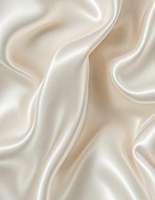 The primary subject of the image is a close-up of a white fabric, possibly silk, with a smooth and shiny texture. The setting is a white background, which provides a clean and minimalist appearance. The visual style is a close-up of the fabric, showcasing its details and texture. The colors and mood of the image are predominantly white, giving it a clean, elegant, and sophisticated feel.